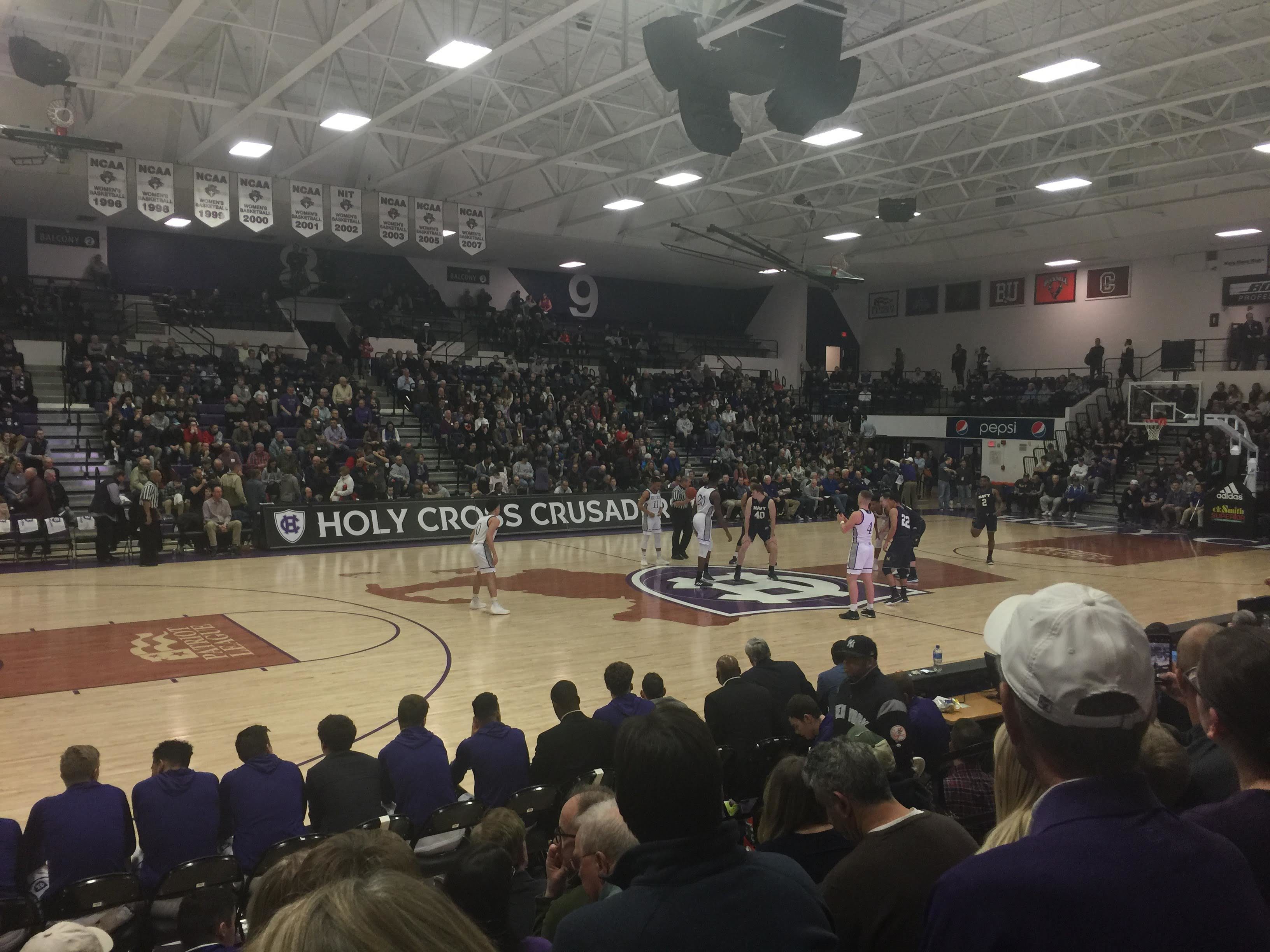 A view from the stands of Holy Cross and Navy basketball players preparing for tipoff.